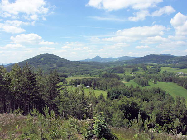 Ausblick vom Jelení vrch (Segenberg) nach Westen. Im Vordergrund links ist der Zelený vrch (Grünberg), rechts weiter entfernt der Trávnický vrch (Glaserter Berg) und in der Mitte ragt am Horizont der spitzige Klíč (Kleis) hervor.