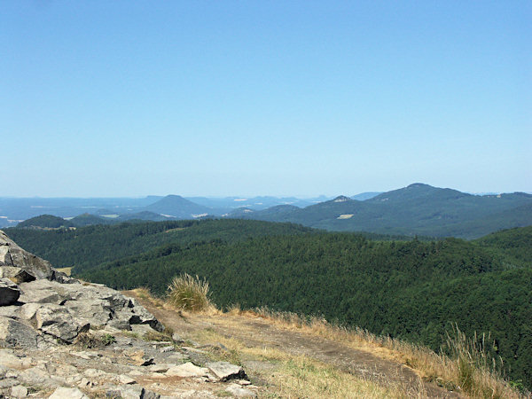Blick vom Gipfel des Klíč (Kleis) nach Westen. Der höchste Berg rechts ist der Studenec (Kaltenberg), im linken Teil ragt der auffallende Růžovský vrch (Rosenberg) empor, hinter dem sich am Horizont der flache Grosse Zschirnstein und die anderen Tafelberge bei Königstein erheben.