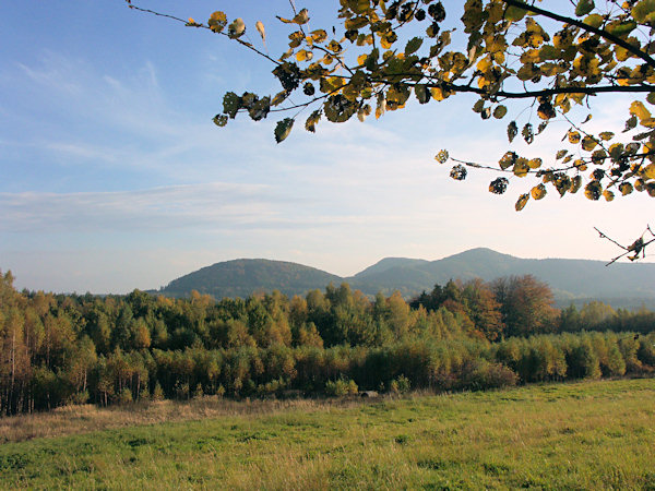 Blick vom Fusse des Strážný vrch (Wacheberg) auf die Berge um Sloup (Bürgstein). Links steht der runde Šišák (Schieferberg), rechts sieht man den spitzigen Slavíček (Slabitschken) und in der Mitte hinter ihm ragt der Tisový vrch (Eibenberg) heraus.