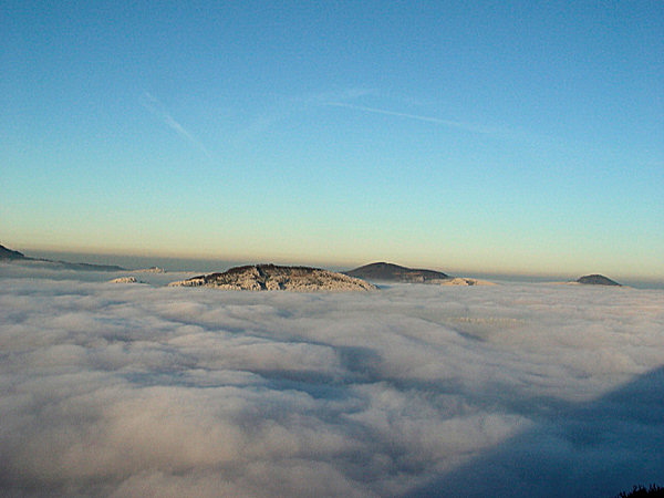 Wie ferne Inseln ragen im Norden der Velký Buk, hinter ihm im Hintergrunde der Pěnkavčí vrch und ganz rechts der Luž aus den Wolken.