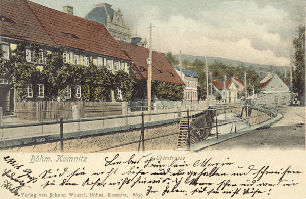 Pohlednice z roku 1903 zachycuje staré roubené domy, které stály až do konce 2. světové války na nábřeží Kamenice před budovou tělocvičny.