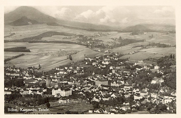 Tato pohlednice zachycuje město ze Zámeckého vrchu. V pozadí za městem je osada Filipov a vlevo na obzoru vyčnívá Růžovský vrch.