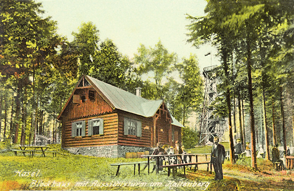 Tato pohlednice zachycuje bývalou horskou chatu na vrcholu Studence s rozhlednou v pozadí.