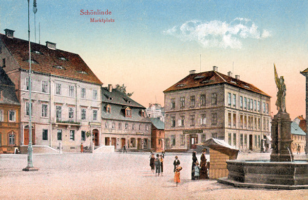Na této pohlednici vidíme severovýchodní část náměstí s výstavnou budovou pošty na nároží vpravo. V popředí je kamenná kašna se sochou Austrie od L. Zimmera, která byla někdy kolem roku 1947 odstraněna.