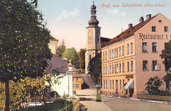 Auf dieser Ansichtskarte aus der Zeit um 1910 sieht man den Anfang der vom Marktplatz in Richtung Rumburk führenden Gasse. Dem Bild dominiert das grosse Gebäude der Post mit der Gaststätte und der Turm der Kirche der hl. Maria Magdalena.