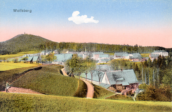 This picture postcard shows the village from the south. In the background there is the hill Vlčí hora with the look-out tower on its summit.