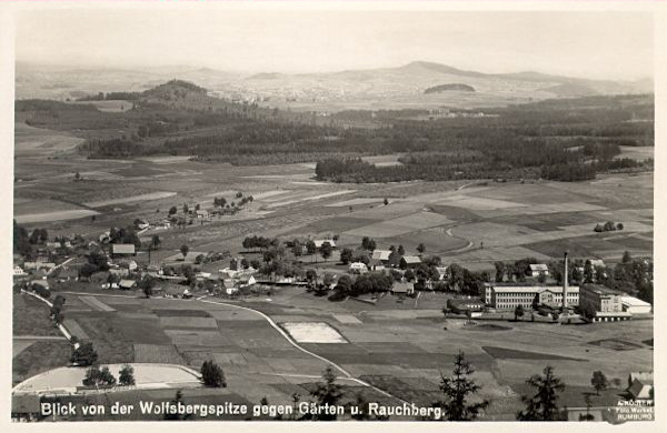 Tato pohlednice zachycuje střední část osady z vrcholu Vlčí hory. Z lesů vlevo vyčnívá vrch Dymník.