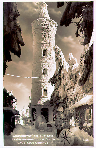 Tato pohlednice zachycuje zimní náladu na vrcholu Jedlové. Prostranství před zasněženou rozhlednou a hostincem je vyzdobeno několika sněhovými výtvory.