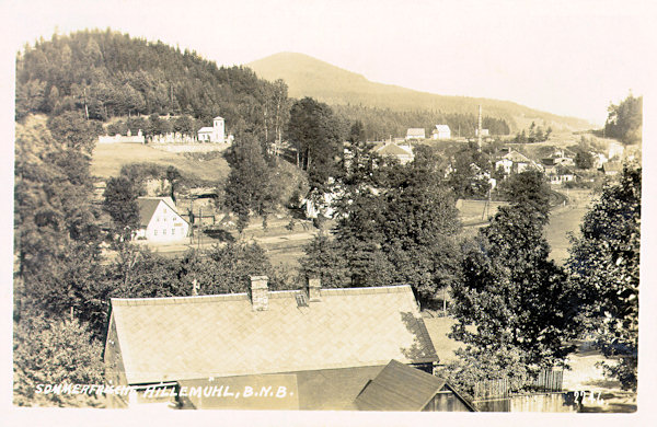 Tato pohlednice zachycuje střední část Mlýnů s hřbitovem na svahu. V pozadí vpravo je bývalá sklářská huť Tereza.