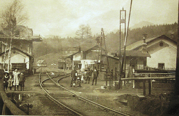 Tato pohlednice zachycuje nádraží v Mlýnech někdy kolem roku 1900 ze směru od Jedlové.