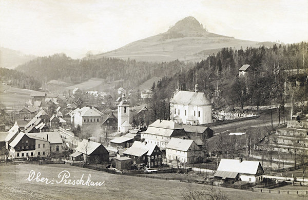 Na této pohlednici vidíme střed obce s kostelem sv. Petra a Pavla, obklopeným hřbitovem se zvonicí. V pozadí je výrazná silueta Středního vrchu.