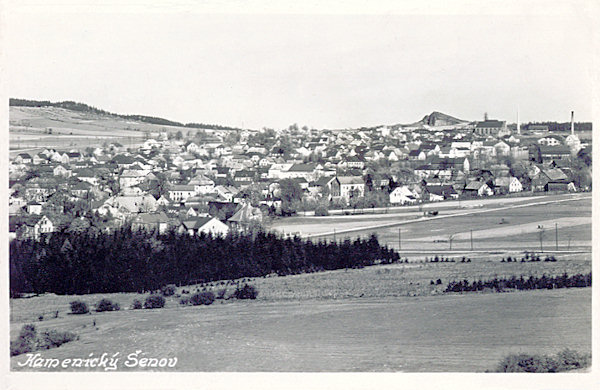 Na této pohlednici vidíme horní část Kamenického Šenova. Z planiny za městem vyčnívá Panská skála a vpravo od ní je Vetterova sklářská huť.
