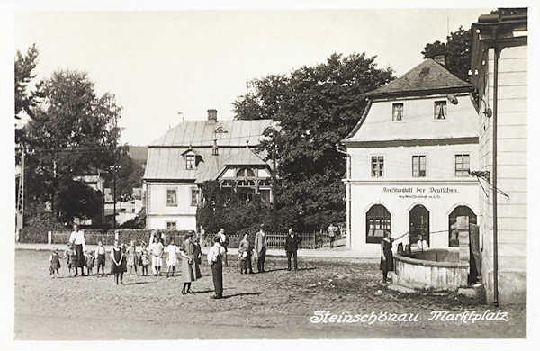 Na této pohlednici vidíme část náměstí s budovou spořitelny „Kreditanstalt der Deutschen“, před níž je kamenná kašna, přistavěná k boční zdi městského muzea. Obě budovy byly později zbořeny a dodnes se dochoval pouze v pozadí stojící dům čp.51.