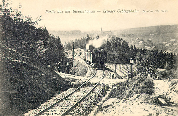 Na pohlednici z roku 1906 vidíme vlak z České Lípy v oblouku trati na svahu Šenovského vrchu. V pozadí je Kamenický Šenov s kostelem.