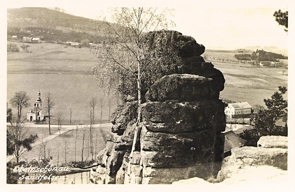 Pohled na dolní konec Kamenického Šenova z vyhlídky na svahu za koupalištěm. U silnice vlevo vidíme později zbořenou kapličku Nejsvětější Trojice.