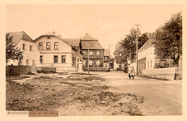 Pohlednice z roku 1915 zachycuje střední část Mistrovic u dnešního obecního úřadu. Zděné domy na levé straně dosud stojí, ale roubený dům za nimi už neexistuje.