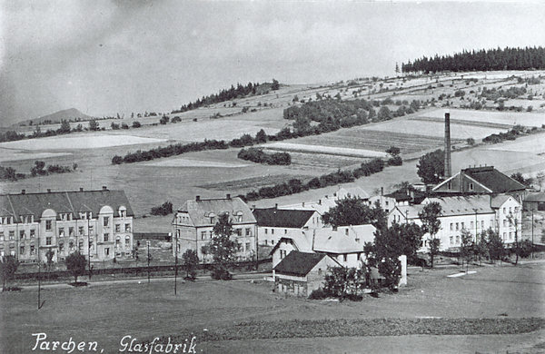 This picture postcard shows the buildings of the former glassworks at the road to Nový Bor as seen from the foot of the Vyhlídka hill. In the background the small fields on the slope of Obrázek hill are seen.