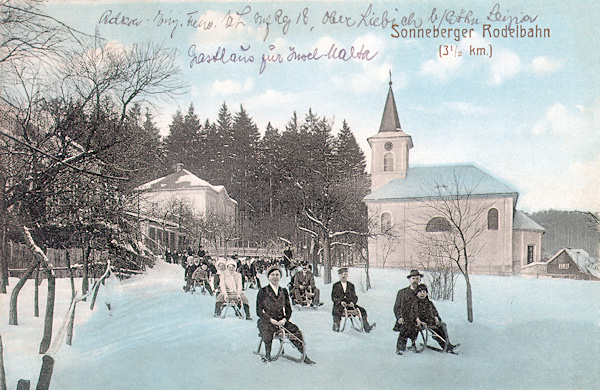 Zimní pohlednice z roku 1917 zachycuje sáňkařskou dráhu na kamenickošenovské silnici, otevřenou místním Horským spolkem v roce 1909. U lesa naproti kostelu je budova fary.