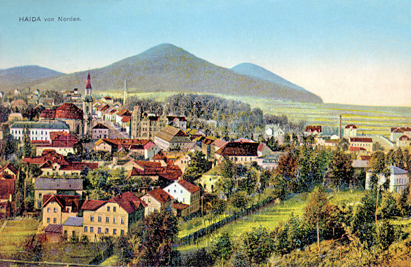 This picture postcard from the years before World War One shows the view of the town centre as seen from the peak of the Borský vrch-hill. In the foreground there are the houses along of the road to Svor, inmidst of the buildings the town square with the church Assumption of the Virgin and the building of the savings bank are seen and between them leads the former Post street (now T. G. Masaryk-street) into the background. On the horizon there is the Chotovický vrch-hill, to the right of it the more distant Skalický vrch-hill and on the left side the lower Lipový vrch-hill.