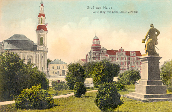 This picture postcard from the years before World War One shows the small park in the northern part of the town square which, then, was dominated by the monument of Emperor Joseph II. In the background there is the church Assumption of the Virgin and the building of the savings bank.