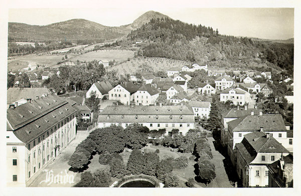 On this picture postcard from the years between both World Wars you see the neatly arranged small park in the norhern part of the town square. In the great building on its left side since 1821 the municipality is located, in the house on the right side in the foreground there is the Glass museum. Over the town rises the low Borský vrch-hill and on the horizon the sharp cone of the Klíč-hill.
