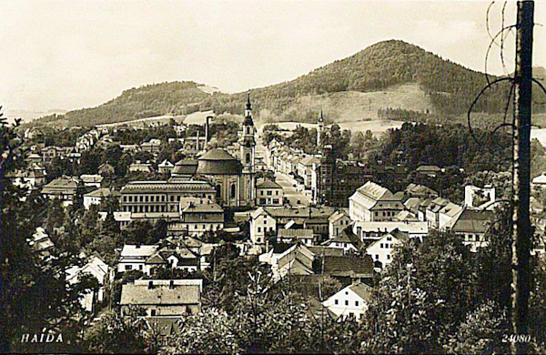 On this picture-postcard from the beginning of the thirties of the 20th century we see the city centre with the church of the Assumtion of Virgin Mary and the main road leading to Česká Lípa. In the background there is the Chotovický vrch-hill.