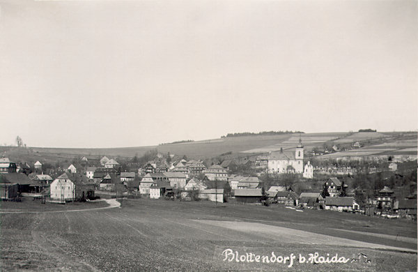 Pohlednice z konce 30. let 20. století zachycuje horní část obce s kostelem Nejsvětější Trojice z jihovýchodu od Jankeho kříže. V pozadí je Polevský vrch.