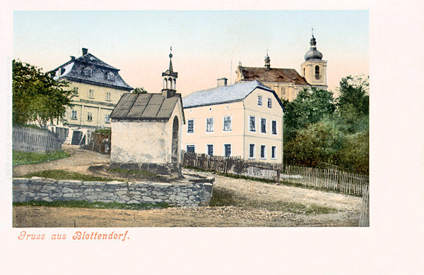 This picture postcard from the first years of the 20th century shows the chapel of Our Lady of Sorrows which at present is yet standing on a crossroad in the upper part of the village. In the background there is the church of St. Trinity. At present between the chapel and the church no one house remained.
