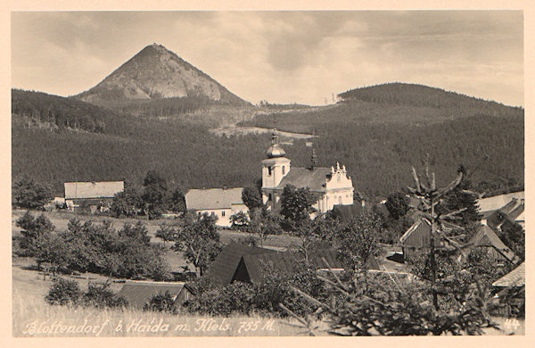 Na této pohlednici vidíme horní část obce s kostelem Nanebevzetí Panny Marie a s výraznou horou Klíč v pozadí.