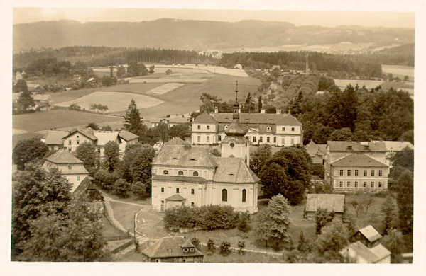 Diese Ansichtskarte zeigt die Anhöhe mit dem Ortszentrum, der Kirche der hl. Katharina und dem Kinskyschen-Schloss. Rechts neben der Kirche steht die Schule, links hinter den Bäumen ist die Pfarrei und hinter ihr das ehemalige gräfliche Hotel.