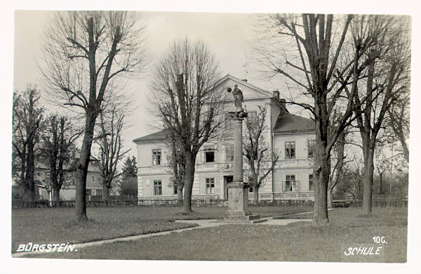 Diese Ansichtskarte aus der Zeit zwischen den beiden Weltkriegen zeigt den Park an der Kirche mit der Mariensäule, die damals in seinem Mittelpunkt stand. Im Hintergrund ist das Gebäude der Schule.
