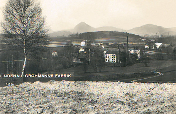 Diese Ansichtskarte zeigt das Areal der heute nicht mehr bestehenden Grohmannschen Färberei am Nordende der Gemeinde an der Strasse nach Cvikov (Zwickau i. B.). Hinter der Fabrik sieht man das Bahnhofsgebäude und am Horizont den heraufragenden Klíč (Kleis).