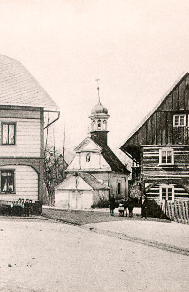 Tato pohlednice zachycuje původní kapli Nanebevstoupení Panny Marie z roku 1725. Kaple stávala na křižovatce v dolní části osady a byla zbořena v roce 1923.
