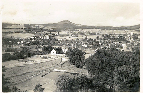 Auf dieser Ansichtskarte sieht man den Südostteil der Stadt um 1957. In der Bildmitte ist die Brauerei, im Hintergrund rechts ragt der Turm der Hl. Elisabeth-Kirche hervor und am Horizont erhebt sich der Strážný vrch (Wachberg).