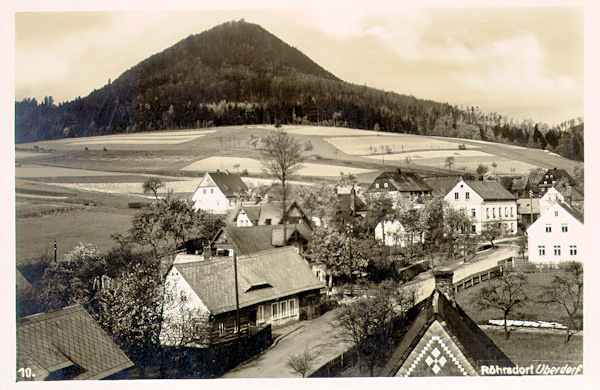 Tato pohlednice zachycuje domky v horní části obce ze železničního mostu. V pozadí je hora Klíč.