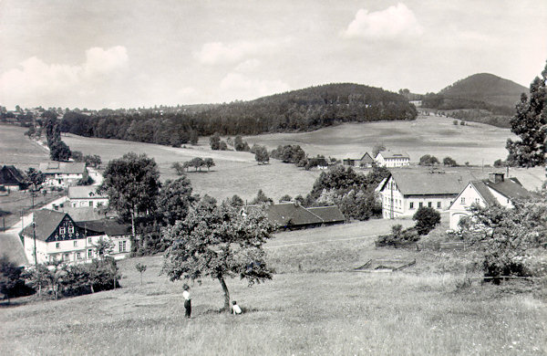 This postcard from the years after World War Two shows the houses standing on the crossroad as seen from the slope under the Plešivec hill. On the lower left side there is the former hotel Schäfer behind of which the road climbs to Horní Světlá. On its right side projects the great house of the hotel Adler and on the horizon behind it there is the Luž hill.