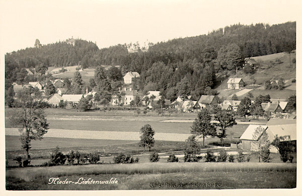 On this picture postcard from the middle of the 30s of the 20th century the houses of the upper part of the village are shown. Near the centre there is the two-storeyed house of the former custom-house and on its left side the small tower of the local chapel. All the houses behind of it in the end of the fifties had been destroyed. On the left side the rock-tower Falkenstein and the roof of the former restaurant „Rabenstein“ on the twin rock Krkavčí kameny protrude from the wood.
