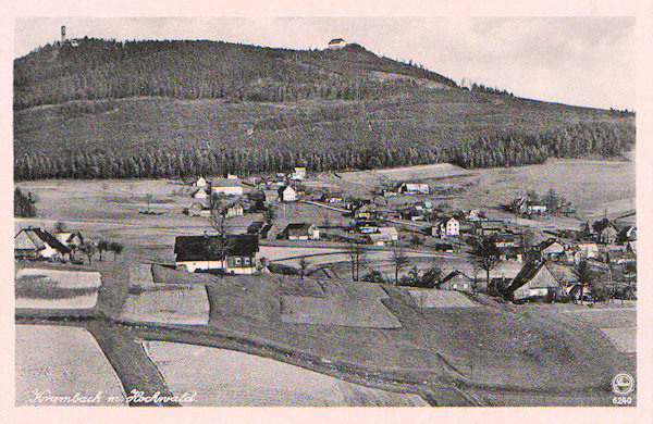 Diese Ansichtskarte zeigt den Blick auf die Häuser des Oberdorfes von Krompach (Krombach) von Nordwest. Im Hintergrund ist der Grenzberg Hvozd (Hochwald) mit dem Berghütte und dem Aussichtsturm.
