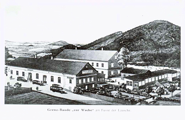 Tato pohlednice zachycuje bývalý hostinec na Wache z české strany hranice. Vpravo je vrch Sonnenberg a v pozadí krajina v okolí Grossschönau.
