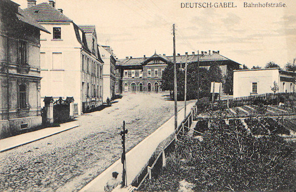 Na této pohlednici vidíme ulici vedoucí z města k nádraží, jehož budova vyniká v pozadí. Po levé straně jsou budovy tehdejší Rautenstrauchovy továrny a vpravo bylo zahradnictví.