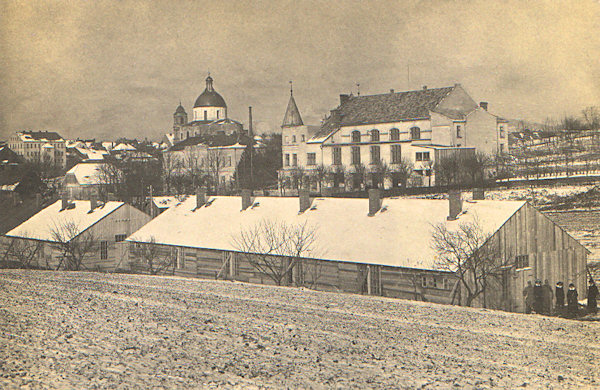 Na této pohlednici vidíme budovu Střelnice s chrámem sv. Vavřince a sv. Zdislavy v pozadí. Dřevěné baráky v popředí byly součástí internačního tábora na Ladech a sloužily k ubytování důstojníků.