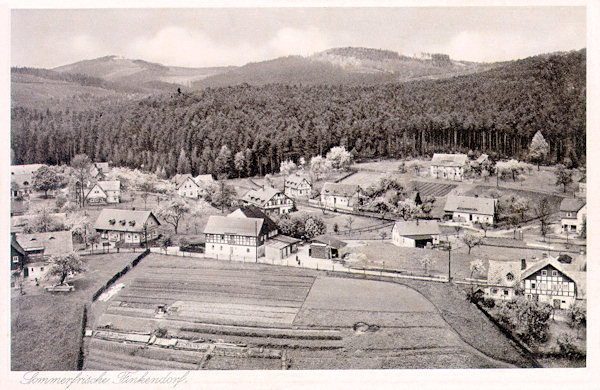 On this picture postcard from the years of about 1930, which was made from the look-out rock Havran we see the houses in the central part of the village. In the center of the foreground there is the former restaurant „Zur Stadt Reichenberg“ and immediately behind of it the restaurant „Zur Quelle“ which to-day serves as boarding-house „U Budulínka“. On the right before the wood stands the boarding-house „Sportturia“.