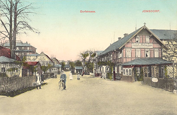 Nedatovaná pohlednice Jonsdorfu zachycuje ulici Dorfstrasse s hostincem Zum Weissen Stein.