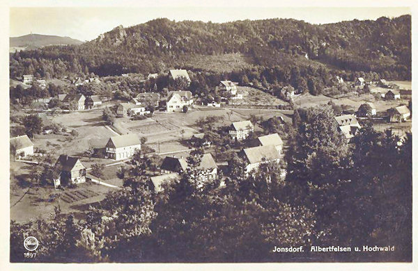 Na pohlednici z roku 1932 vidíme západní část Jonsdorfu. Za obcí je zalesněná skalní oblast Mühlsteinbrüche a v pozadí Hvozd s rozhlednou.
