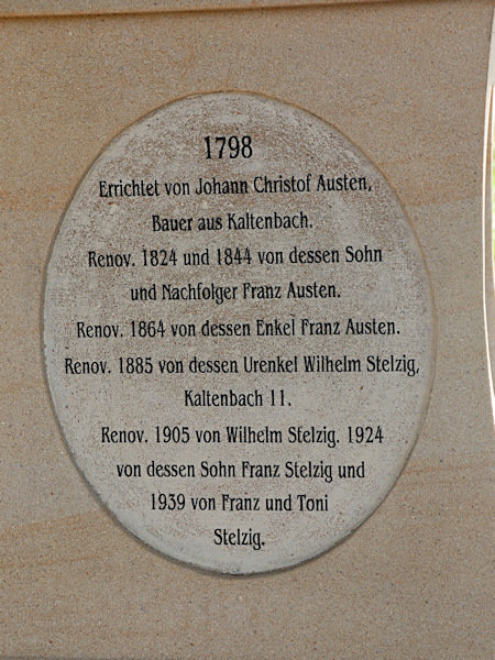 Nápis na zadní straně kříže shrnuje historii jeho vzniku a renovací.