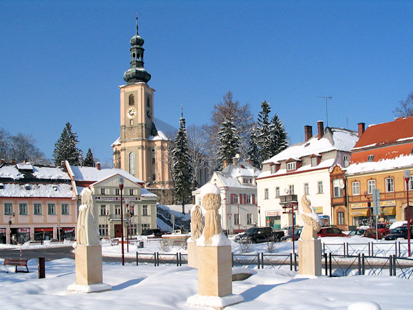 Zimní pohled na náměstí se symbolickým mostkem a sochami čtyř přírodních živlů.
