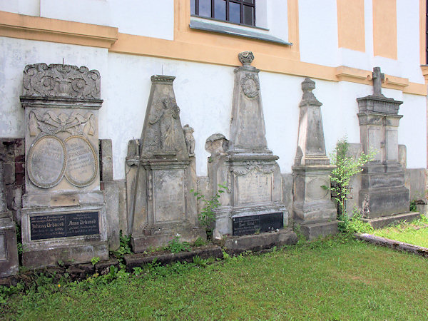 Alte Grabsteine an der Kirchenwand.