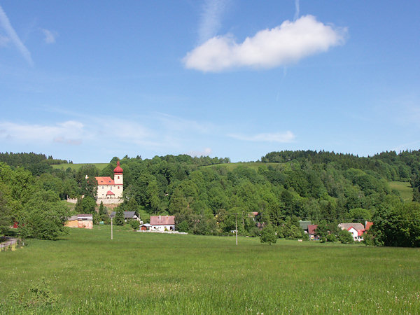 Horní část obce s kostelem Nejsvětější Trojice. V pozadí je Polevský vrch.