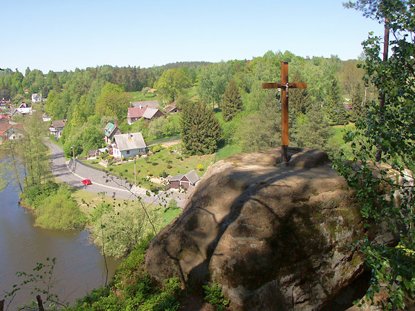 Felsen mit dem Holzkreuz am Rande des Hügels über dem Teich.